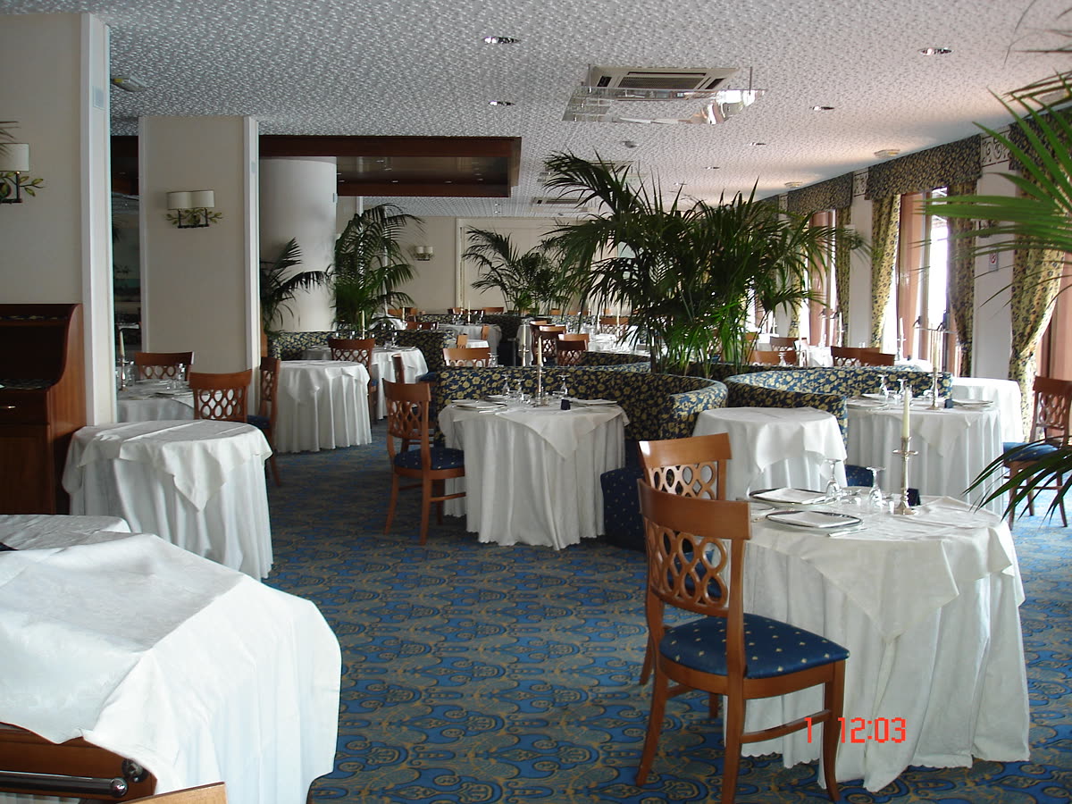 Il ristorante verso le vetrate e le piante in vaso.
