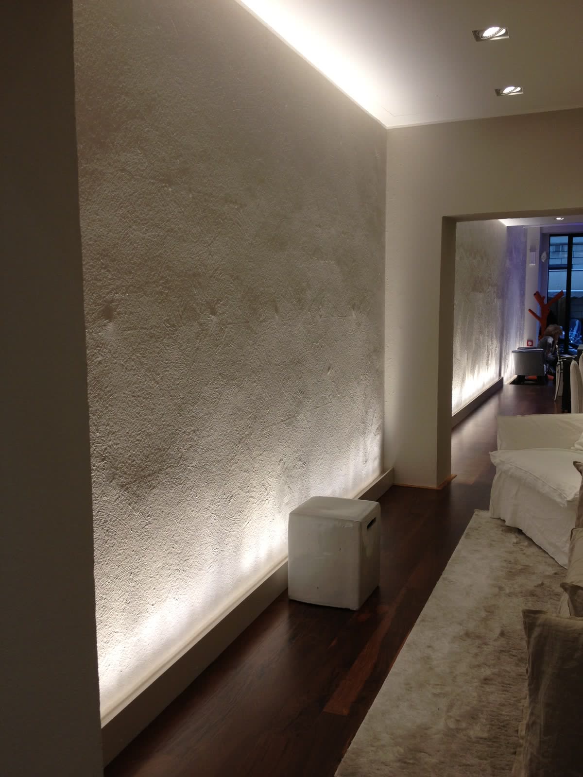 Parete materica dello showroom illuminata di taglio.