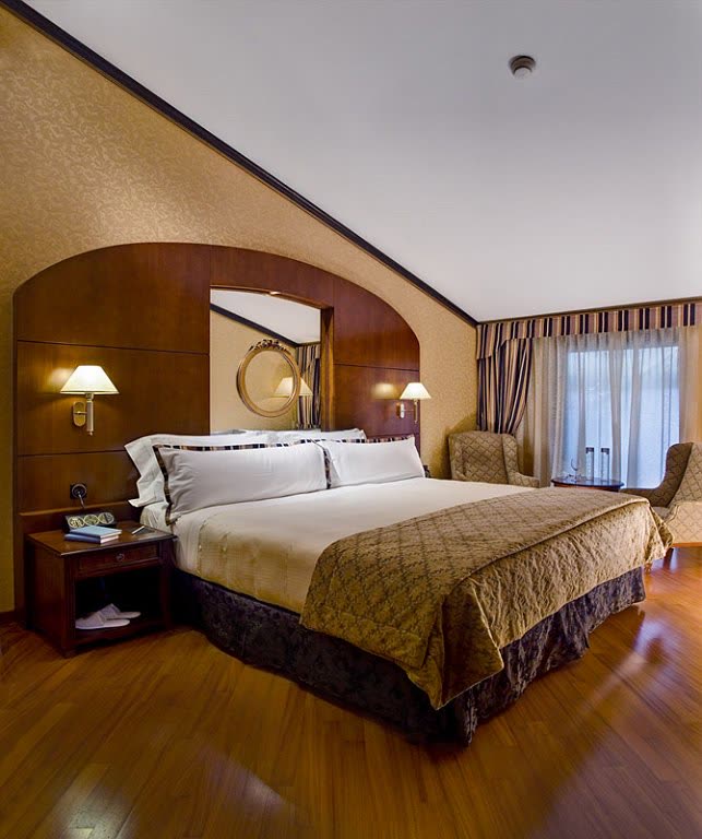 Camera della suite con testata curva in legno.