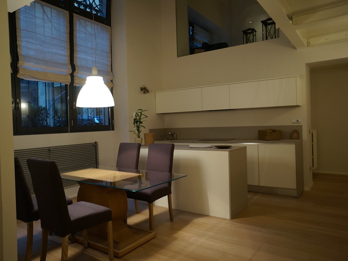 La cucina e la zona pranzo, con il tavolo sotto la lampada.