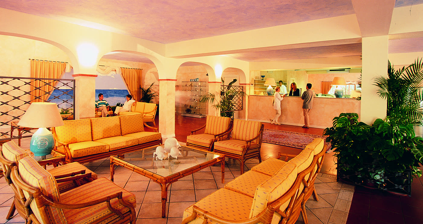 Hall del resort con divani in midollino e archi bianchi.